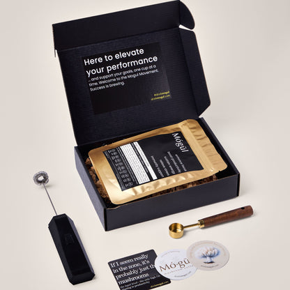 The Mógūl mushroom coffee kit comes with one 30 serving pack of mushroom coffee, a handheld frother, a gold measuring spoon, and 3 branded stickers.